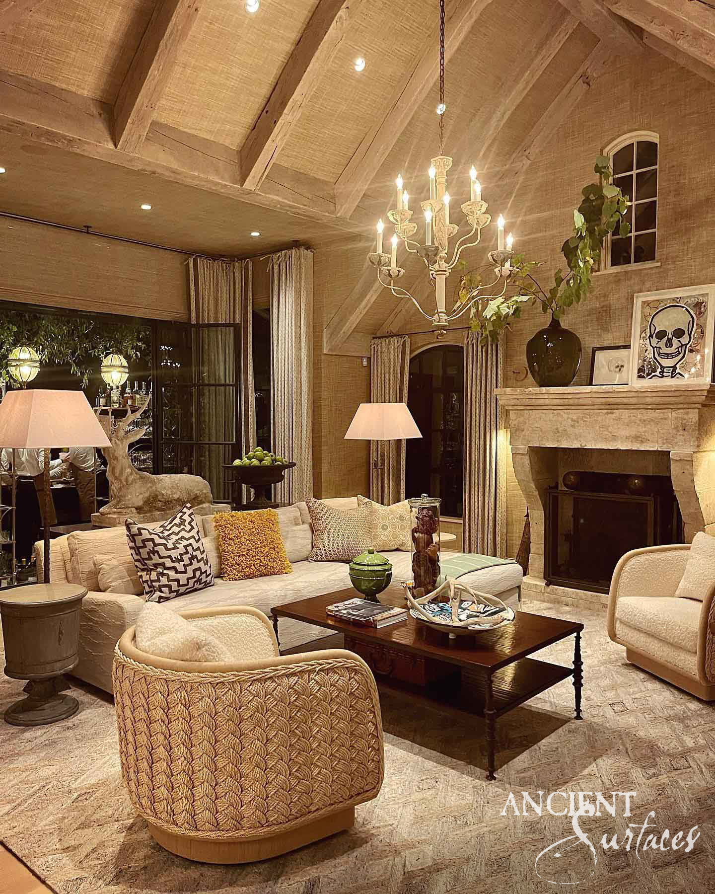 Reclaimed antique limestone mantel from Ancient Surfaces at the side of a vaulted evening living room, with a thick projecting moulded shelf, a plain panelled frieze and broad curved console legs