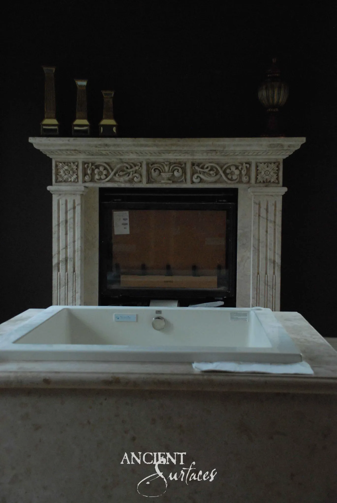 Reclaimed antique limestone mantel from Ancient Surfaces with a dentil band under the shelf, a carved foliate frieze with a central palmette and rosette end blocks, carried on fluted pilaster legs